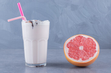 Ripe grapefruit with freshly made milk shake on table close-up