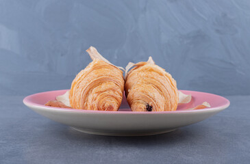 Two Fresh French croissant on plate over grey background