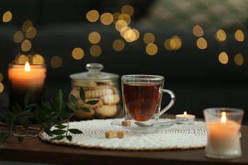 Fototapeta na wymiar Tea, cookies and decorative elements on wooden table against blurred lights indoors