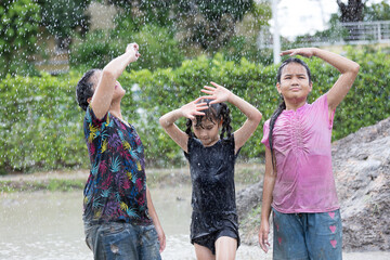 Group of happy children girl playing in wet mud puddle during raining in rainy season