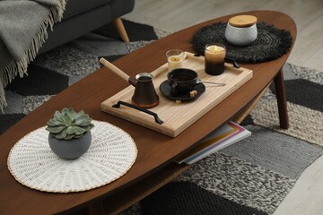 Tray with freshly made coffee and decorative elements on wooden table in room