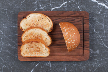 Three toasts arranged and bun on the board, on the marble background