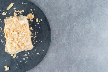 A piece of delicious Napoleon cake on a dark board