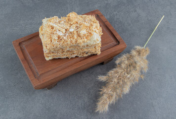 Delicious piece of Napoleon cake with wheat on a wooden board