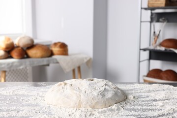 Fresh dough with flour on table in kitchen