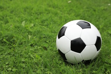 Fototapeta na wymiar Football ball on green grass outdoors, space for text