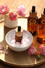 Fototapeta na wymiar Bottles of rose essential oil and flowers on wooden table
