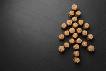 Christmas tree made of sparkling wine corks on black background, flat lay. Space for text