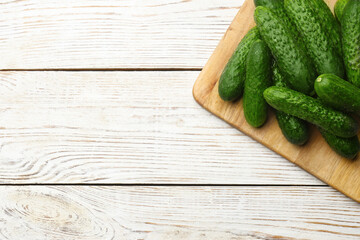 Fresh ripe cucumbers on white wooden table, top view. Space for text