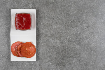Fototapeta na wymiar Delicious grilled salami and ketchup on white plate