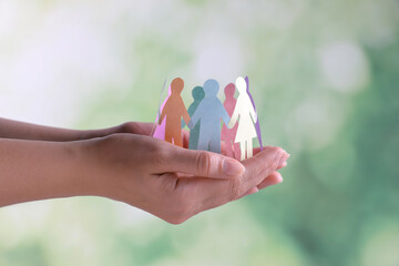 Woman holding paper human figures on blurred background, closeup. Diversity and Inclusion concept