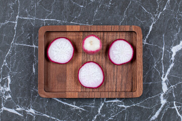 Sliced red radish on wooden plate