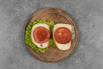 Tasty sausage with bread slices on wood piece