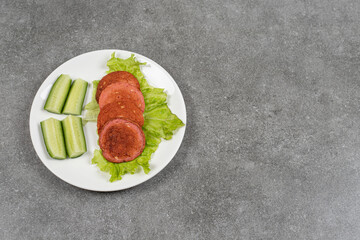 Sliced grilled sausages and cucumber on white plate