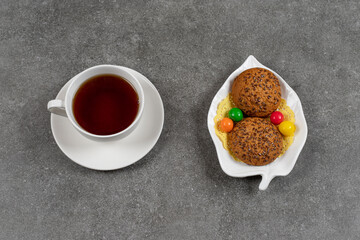 Cookies with candies on white plate and cup of tea