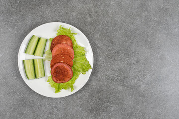 Sliced grilled sausages and cucumber on white plate