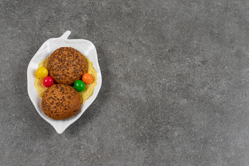 Delicious sweet cookies with candies on white plate