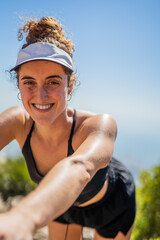 Blonde caucasian green eyed woman with a visor smiling in the mountains