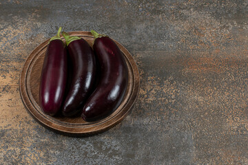 Raw aubergine on the board , on the marble background