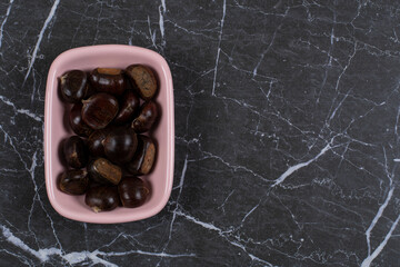 Chestnut in the pink bowl, on the marble background