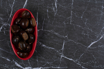 Toothsome chestnut in the red bowl, on the marble background