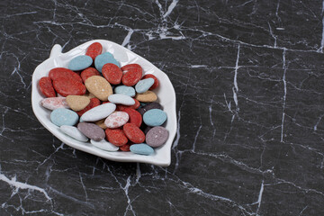 From each other delicious candies in the bowl, on the marble background