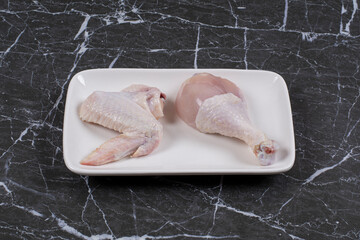 Bird wing and drumstick in the plate , on the marble background