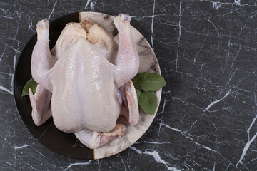Composition with whole raw chicken, on the marble background