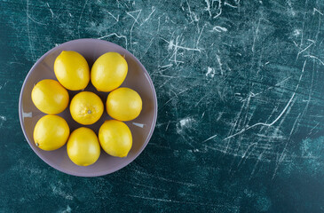 Sour yellow lemons on purple plate