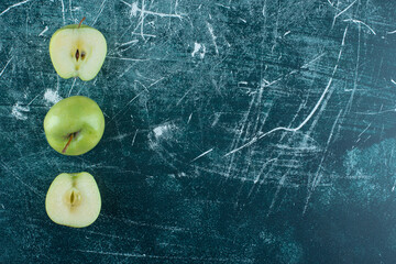 Sliced and whole green apples on marble background