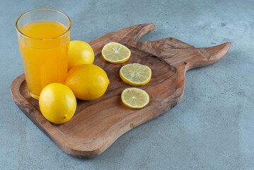 A glass cup of orange juice with fresh lemons