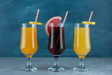 Three various juices in glass cups with straw