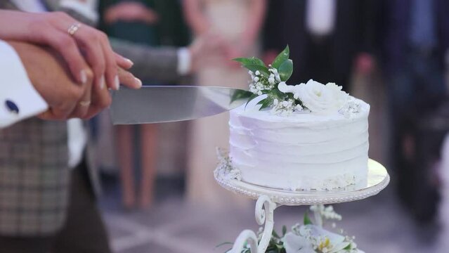 Newlyweds cut the wedding cake, close-up. The bride and groom holding a knife