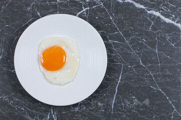 Tasty fried egg on the plate , on the marble background