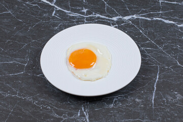 Delicious fried egg on the plate , on the marble background