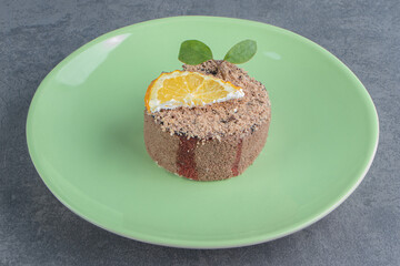 A green plate with cupcake and slice of lemon