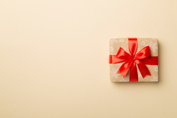 Gift box with red ribbon bow on color background, top view