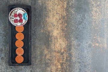 Tasty cupcake decorated with cream and candies on black plate