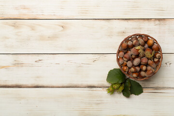 Hazelnuts with green leaves on wooden background, top view