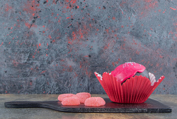 Cookie with pink glaze and candies on black board