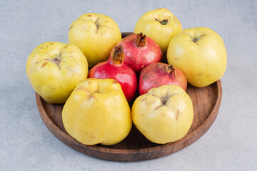 Fresh and organic apple quince and pomegranate on wooden board