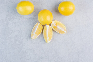 Pile of yellow fresh lemon and slices on grey background