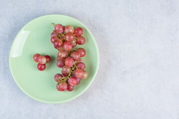 Red fresh organic grape bunch on green plate