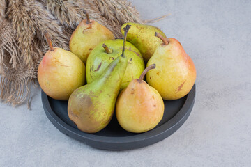 Pile of colorful pears on black plate