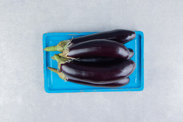 A stack of eggplants on a tray on the marble background