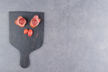 Tomato and sausage with ketchup on the board, on the marble background