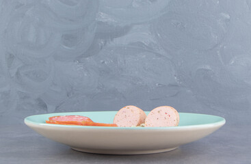 A sliced of sausages on the plate , on the marble background