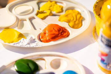 paints and brushes in the process of work, palette with mixed paints, all colors of the rainbow in paints