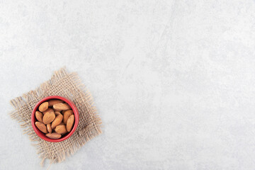 A bowl of almonds, on the trivet, on the marble background