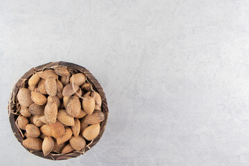 A pile of almonds in the bucket, on the marble background